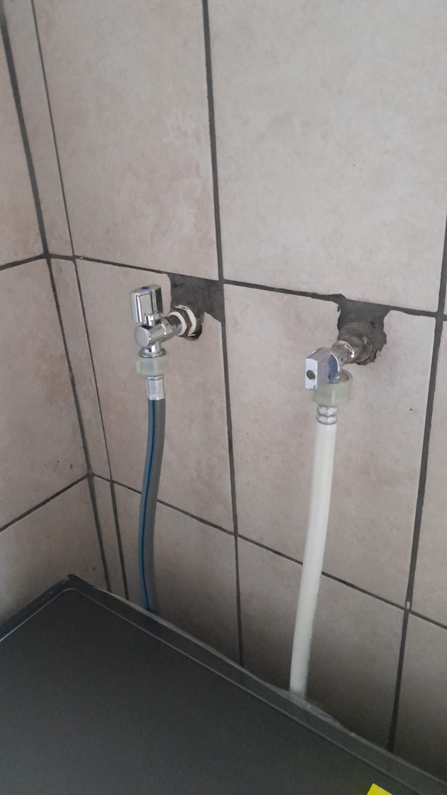 Dishwasher isolation valves and water connections on tiled wall