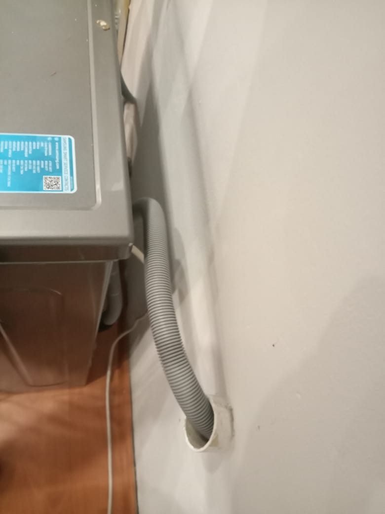 Dishwasher hose route through wall opening