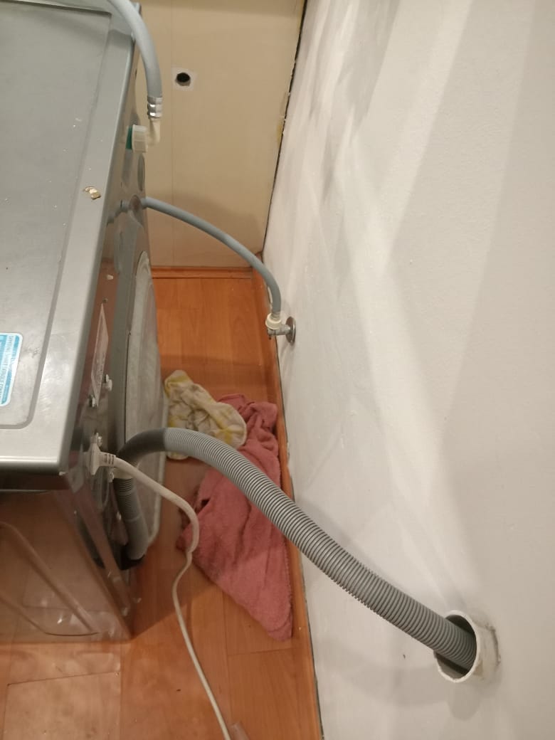 Dishwasher water supply hose and valve connection behind appliance