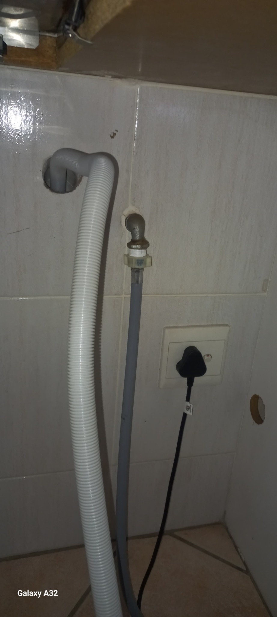 Dishwasher waste hose and pipework behind appliance