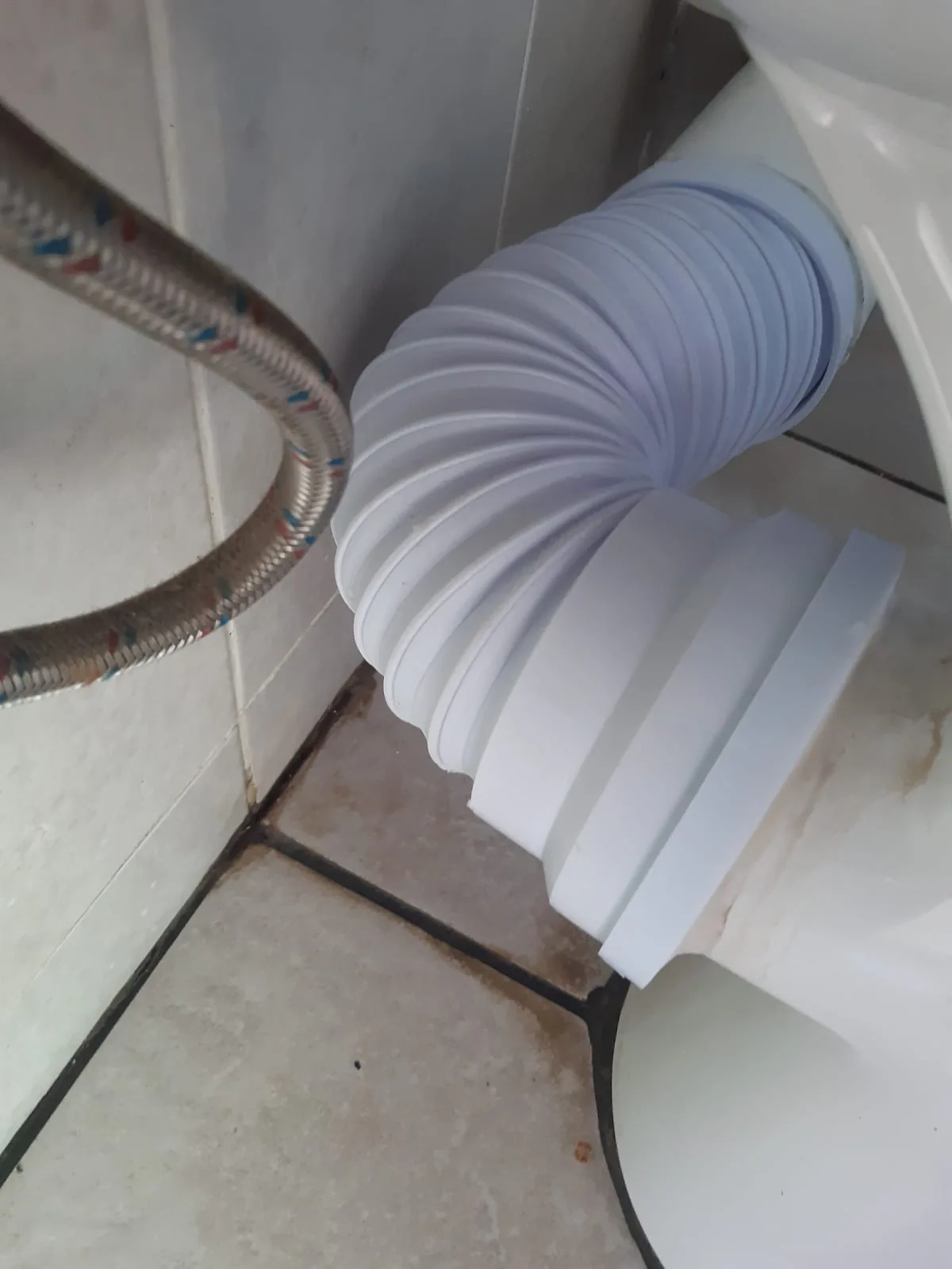 Flexible toilet pan connector fitted behind a toilet during leak repair work