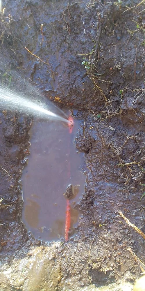 Underground burst pipe spraying water inside an excavated trench