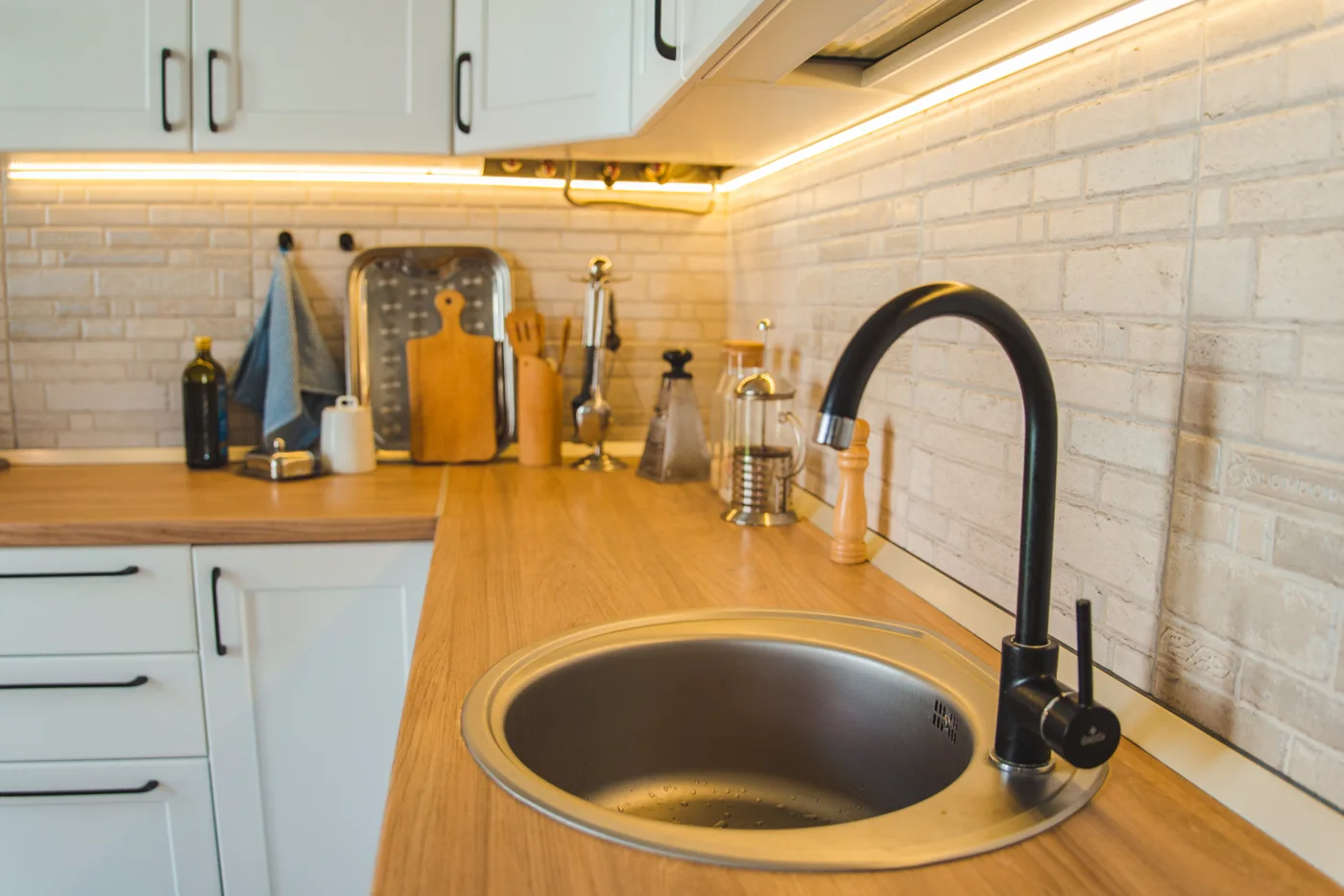 Kitchen makeover design example White kitchen cupboards above a timber worktop with a round sink and black mixer