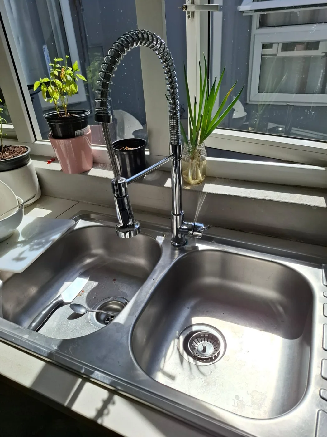 Kitchen renovation quotes — Sink and mixer details for a renovation quotation Stainless steel double kitchen sink with a spring-neck mixer beside a window