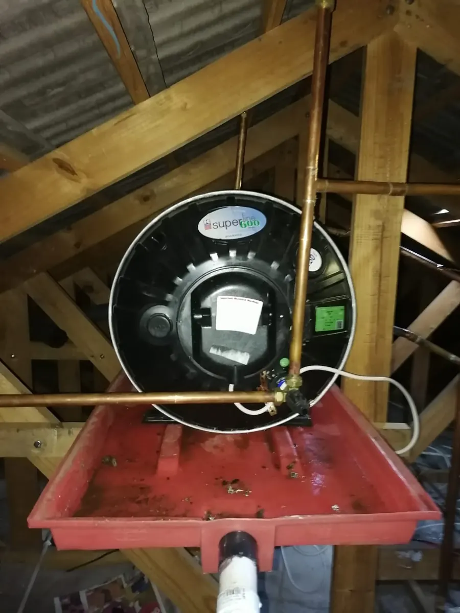 Burst geyser isolated in a roof space drip tray before replacement work begins