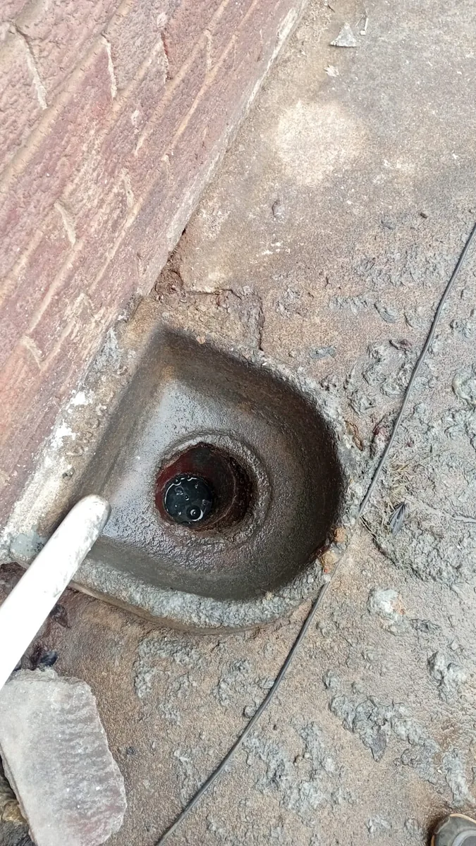 Blocked outside gulley cleaned near a wall and paved area