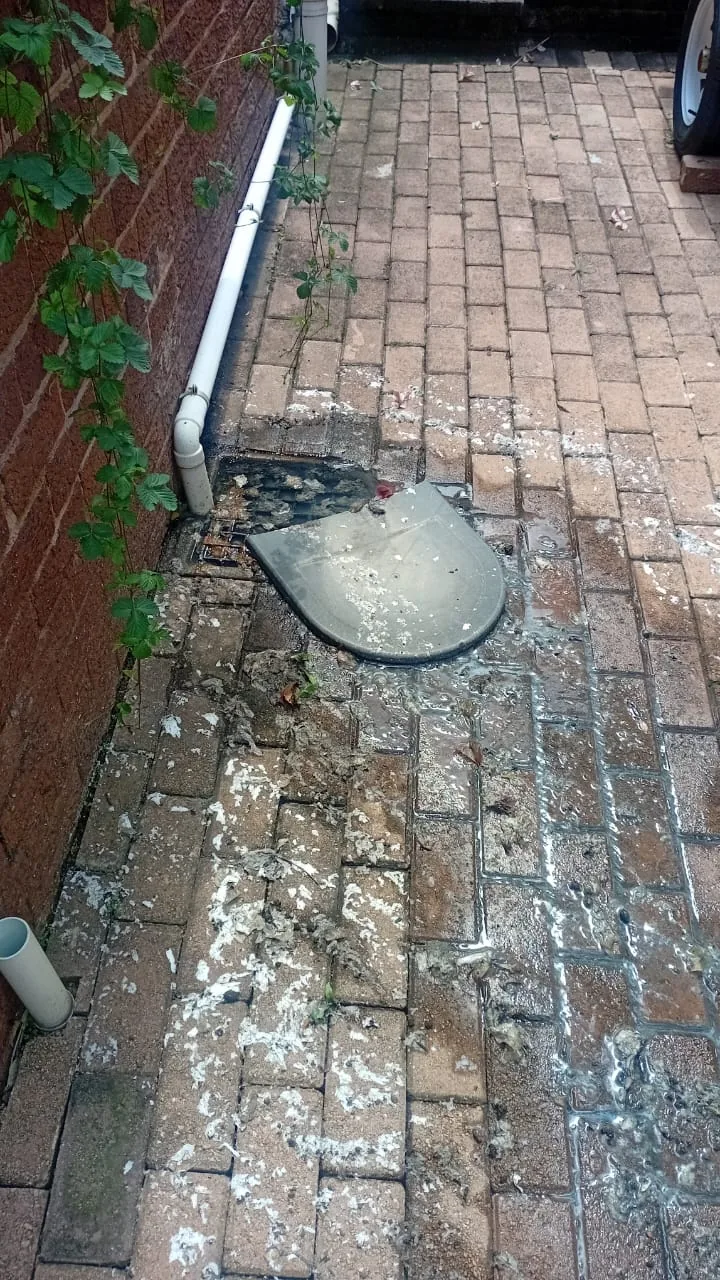 Outside gully overflowing with wastewater and debris around paving