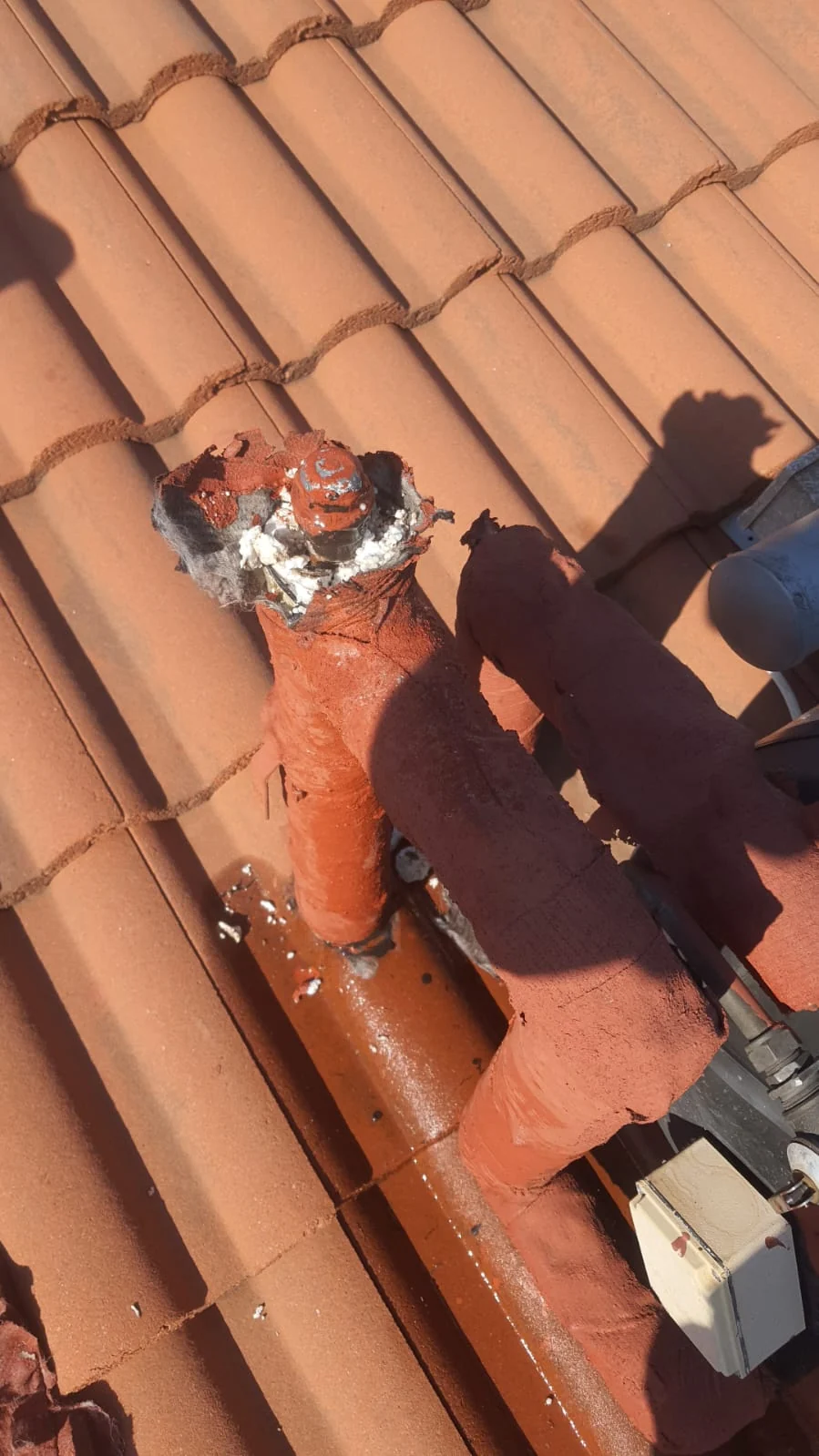 solar geyser pipe penetration on tiled roof with sealant and waterproofing repair area