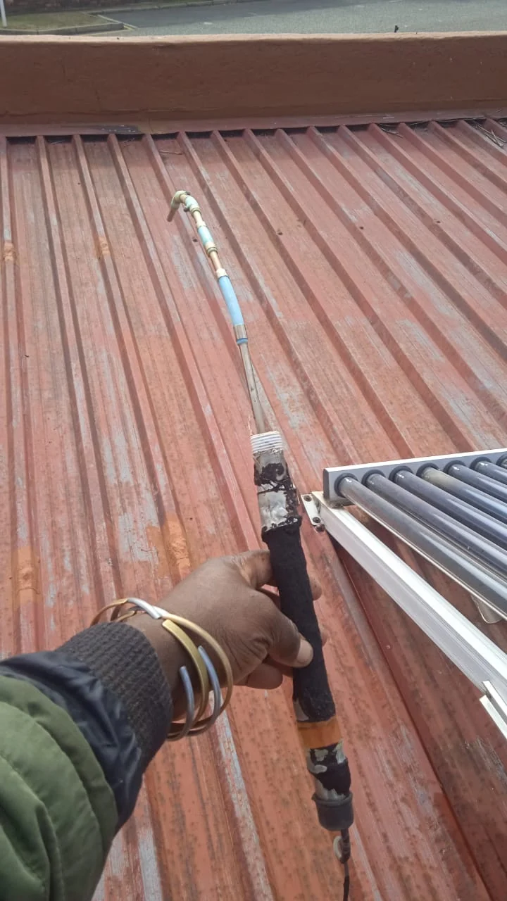 solar geyser roof pipework with insulation being checked near evacuated tube collector