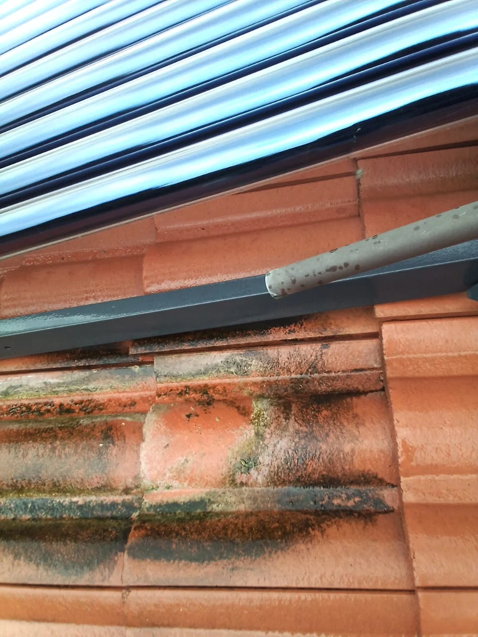 roof tiles stained below a solar geyser collector pipe showing possible leak or overflow problem