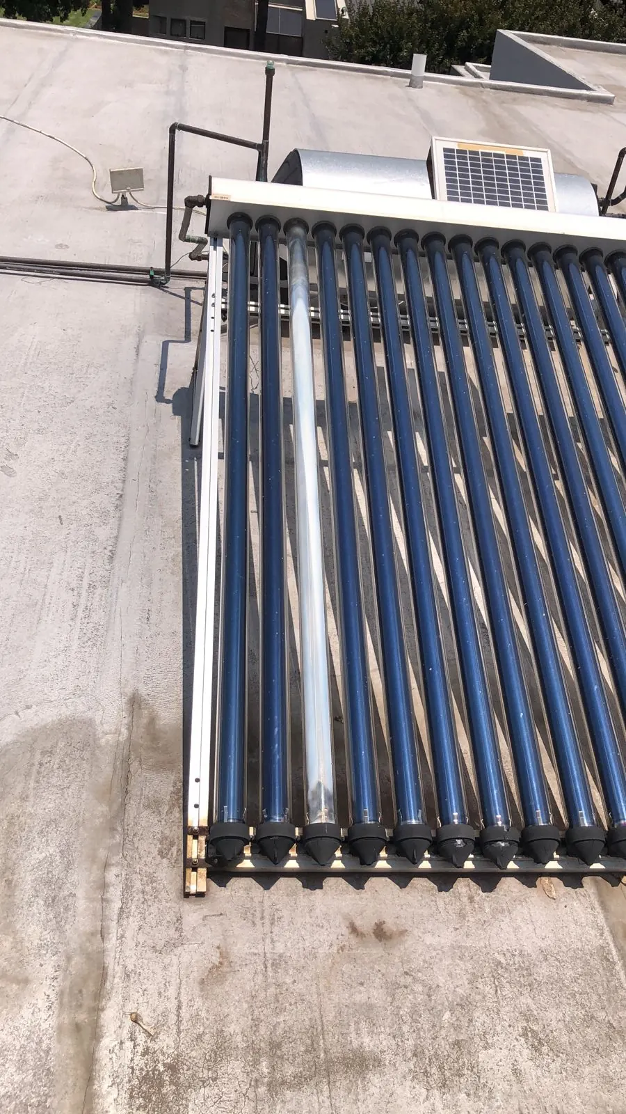 Evacuated tube solar geyser with small PV panel on a flat roof