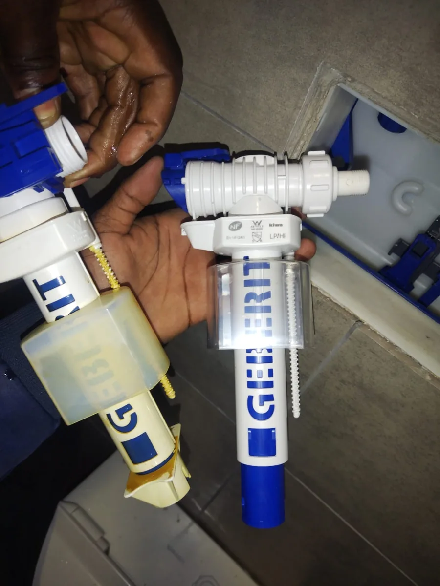 Geberit toilet fill valve and old fill valve parts held during replacement