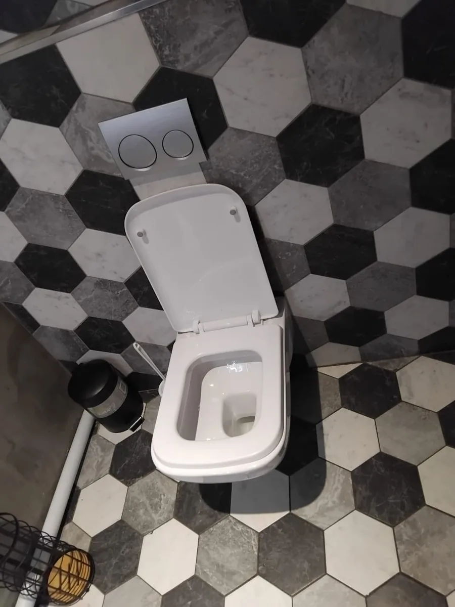 Wall-hung toilet installed against patterned bathroom tiles