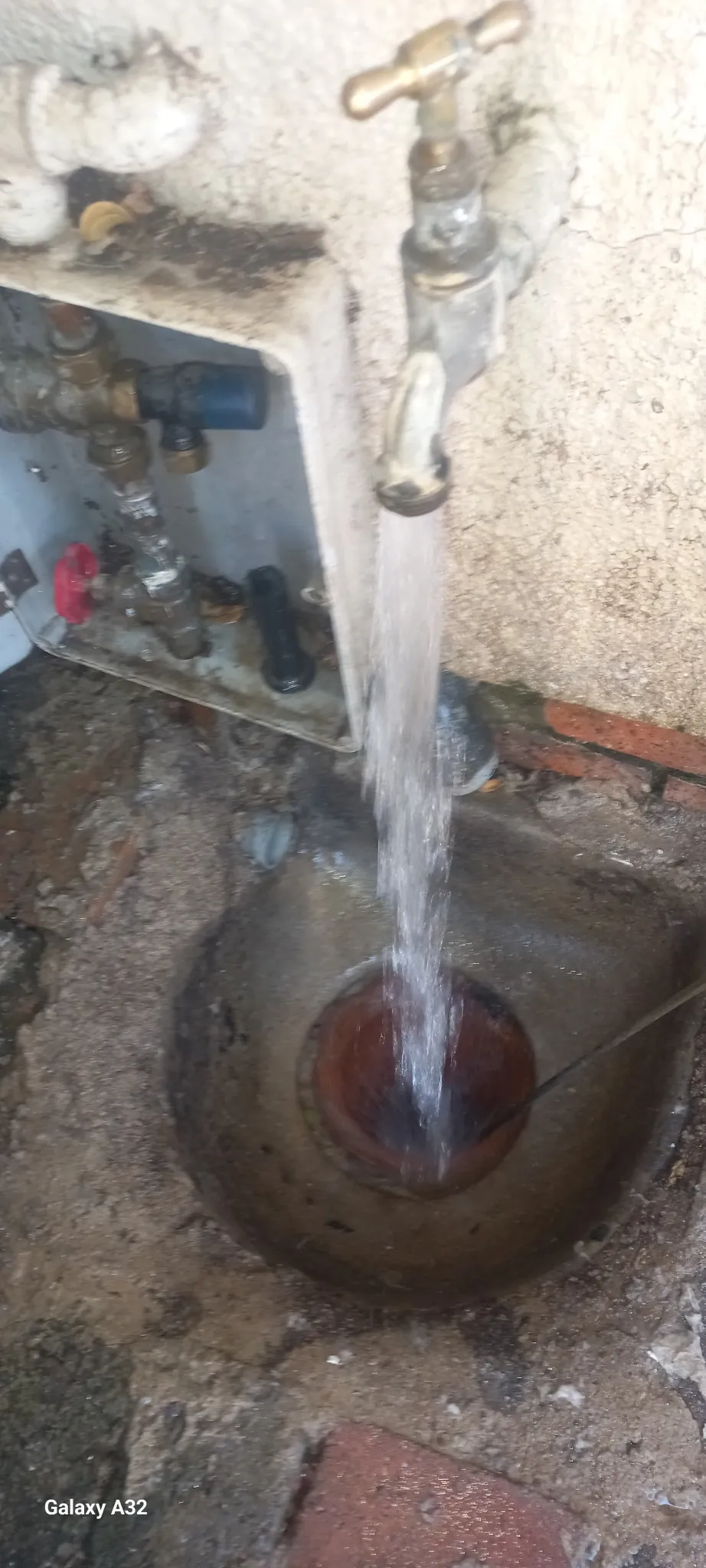 Water running from an outside tap into a drain opening during drain flow testing