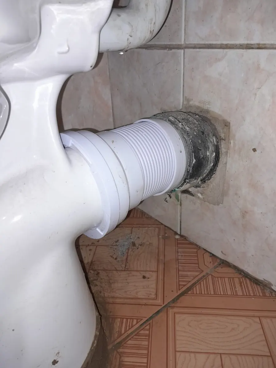 Toilet pan connector installed between toilet and tiled wall