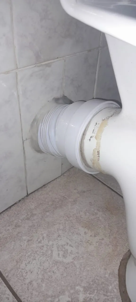 Toilet pan connector repaired behind toilet at tiled wall
