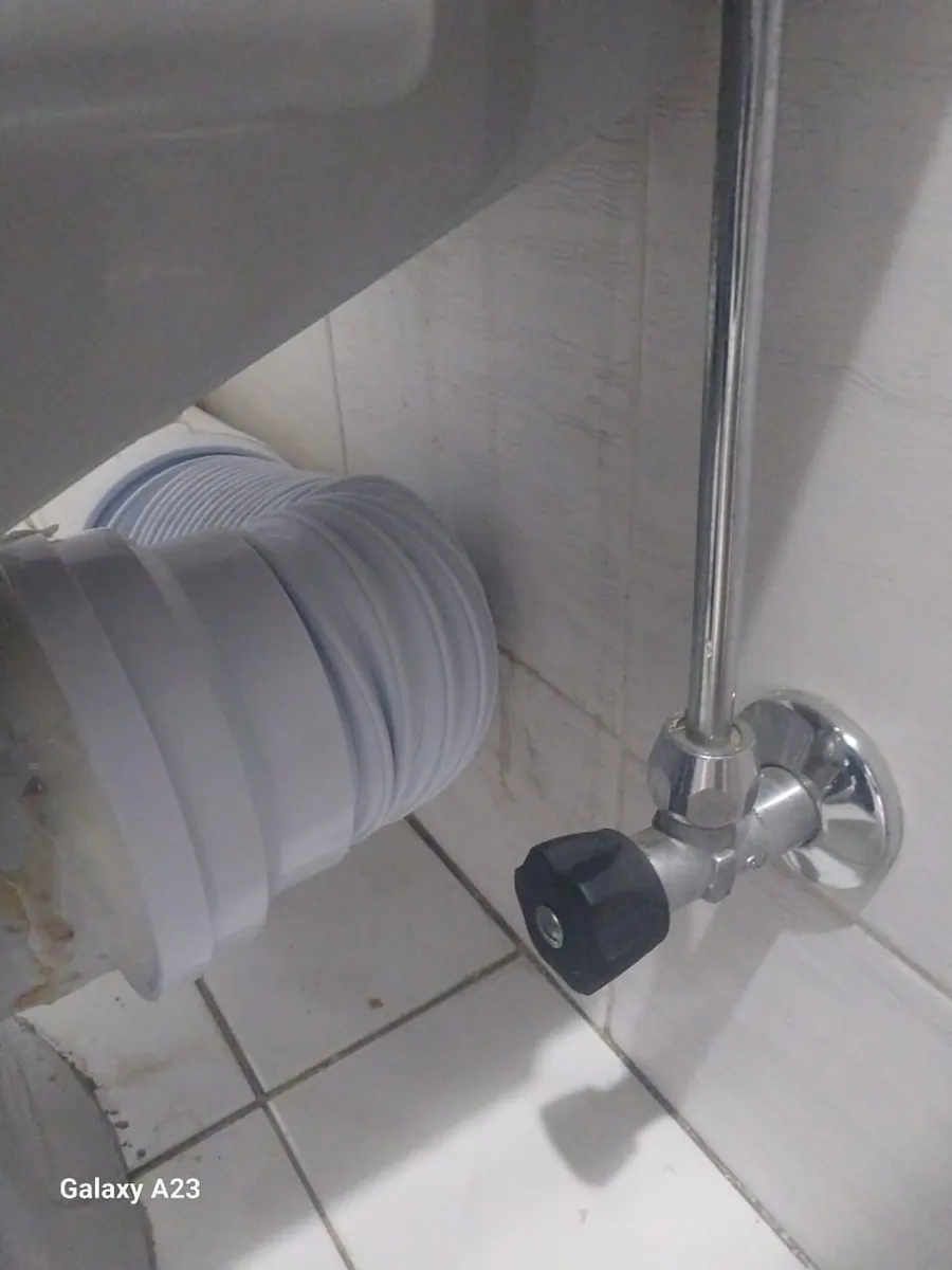 Toilet waste connector and braided supply hose behind toilet