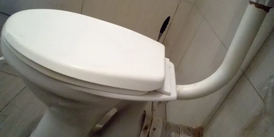 Side view of toilet with waste pipe connection behind pan