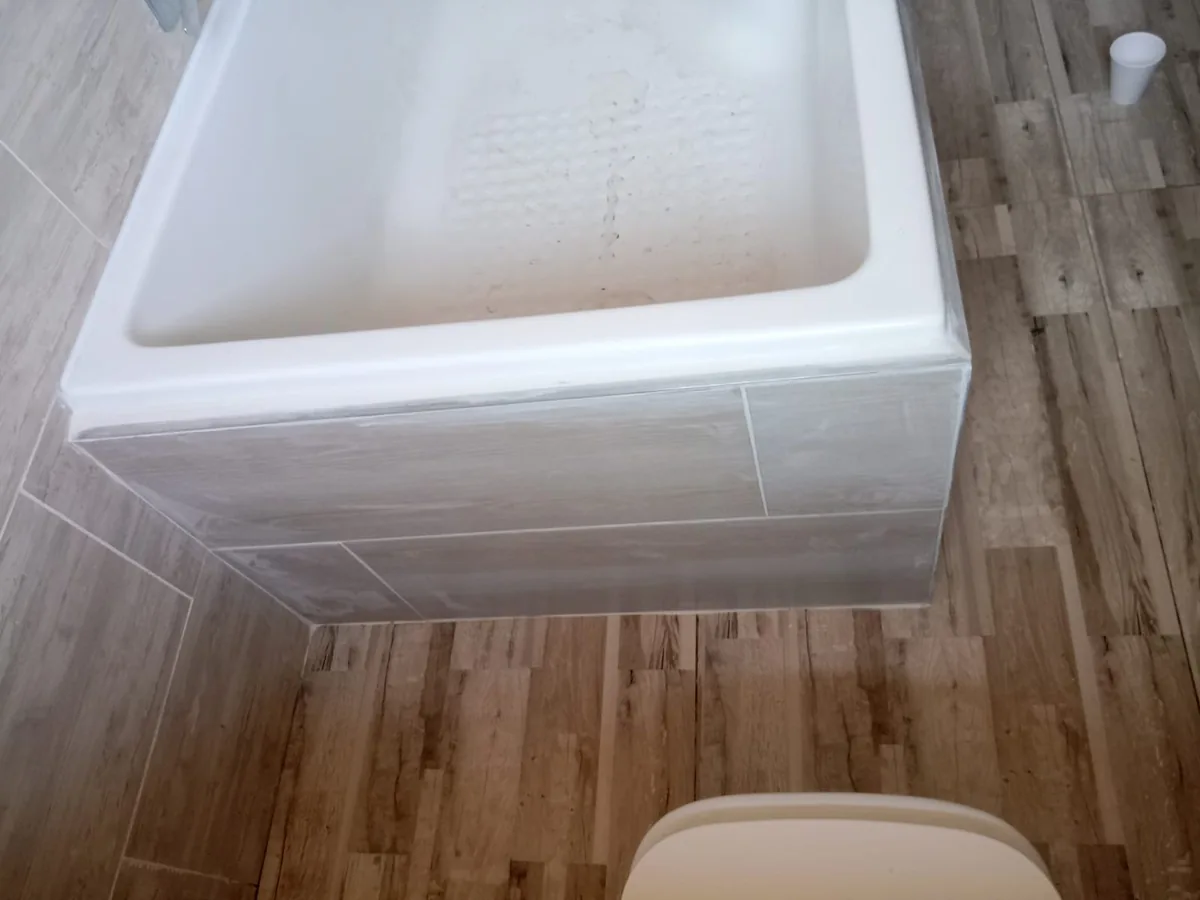 Bathtub installed with tiled panel during bathroom renovation