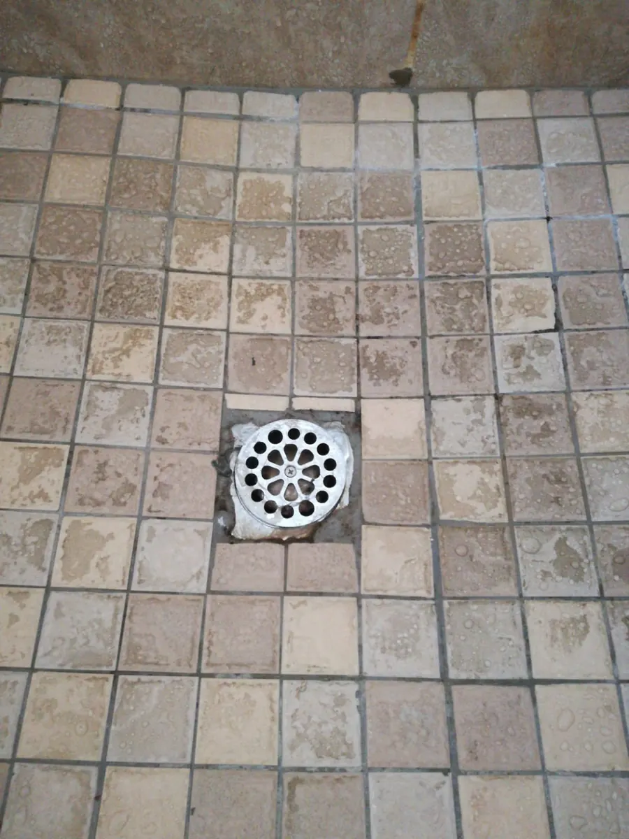 Clean shower drain cover on wet tiled floor after drainage service