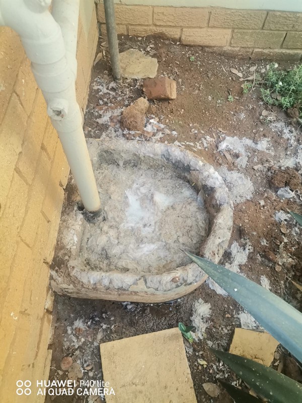 Hands performing repair on a blocked drain