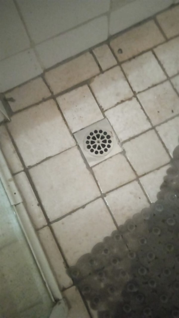 Hands performing repair on blocked shower drain