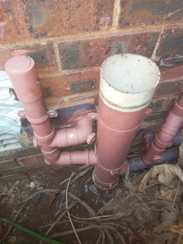 Plumber clearing blocked sewer pipe with tools visible