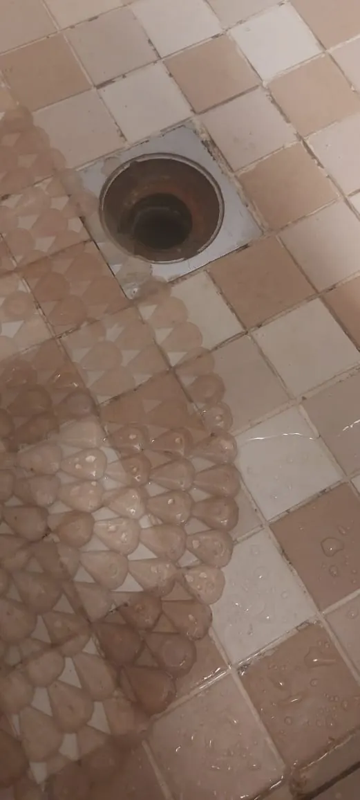 Open shower drain outlet showing water flow path for blocked shower service