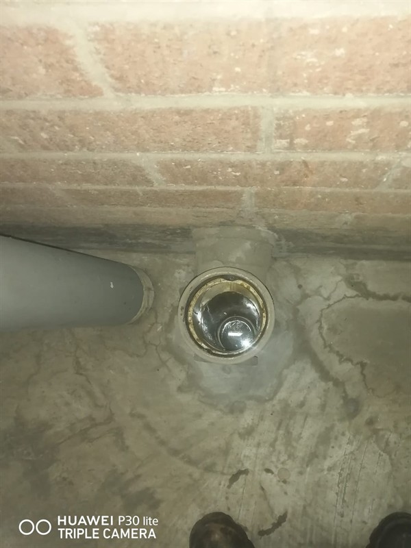 Plumber actively clearing a blocked drain pipe with tools visible