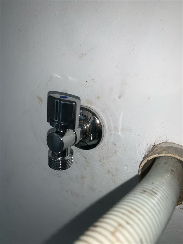 Technician working on washing machine angle valve replacement