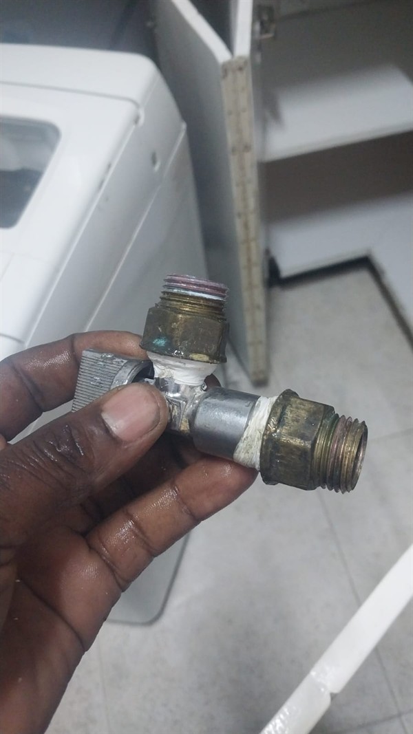Close-up of leaking washing machine angle valve with water droplets visible