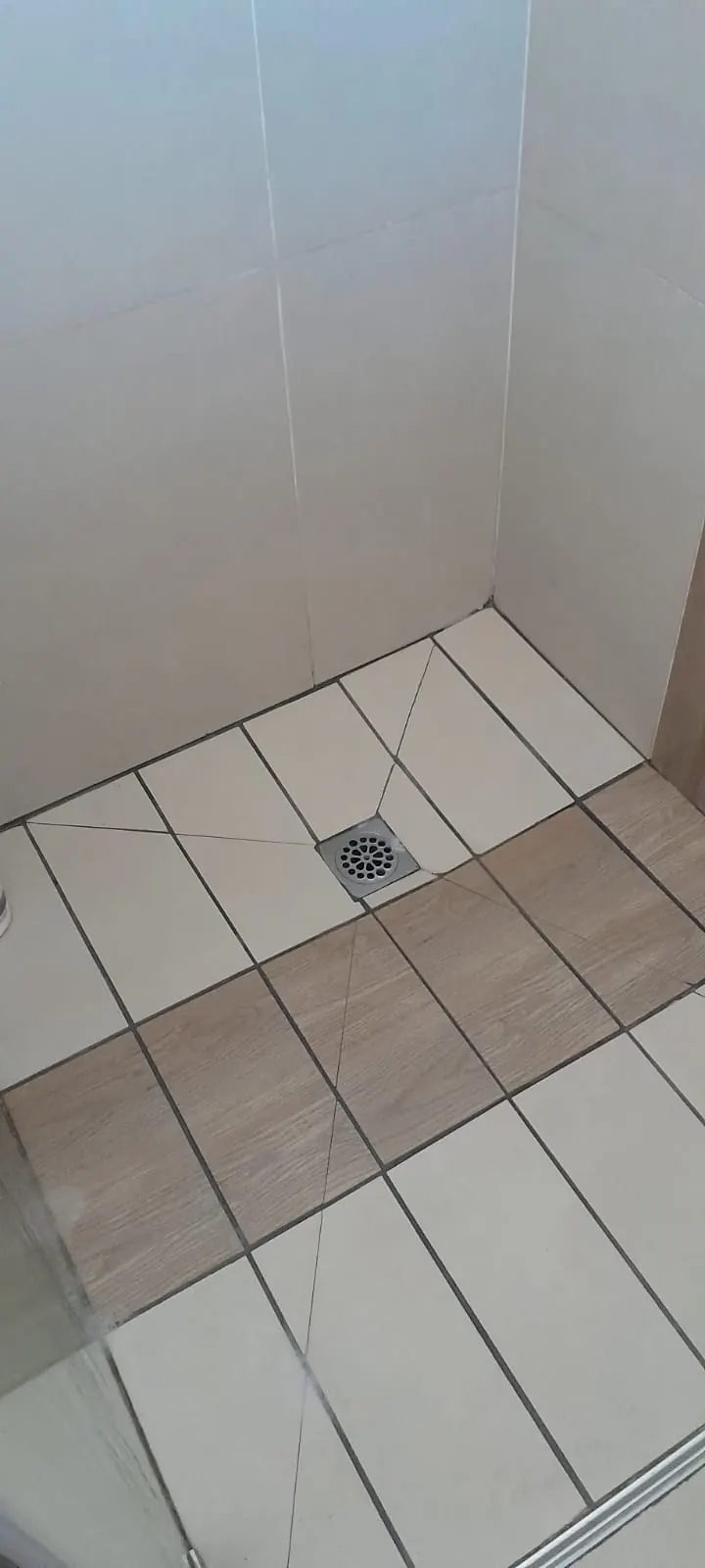 Shower floor drain positioned in tiled shower area for maintenance checks