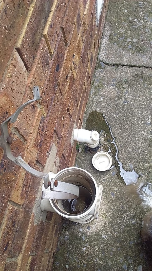 Plumber clearing a blocked drain pipe using professional tools