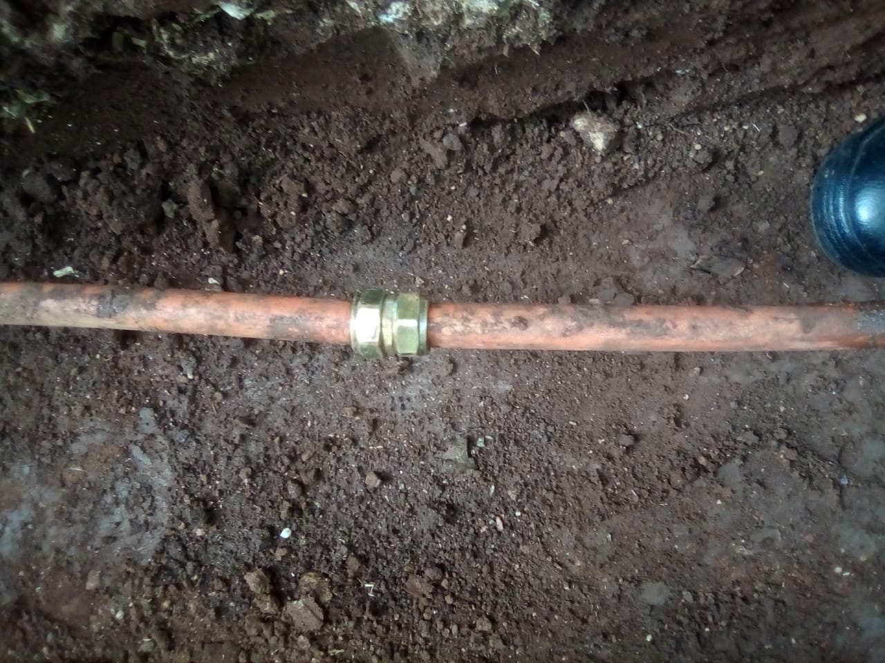 Underground burst copper water pipe repaired in Primrose with compression coupling installed in excavated soil trench, showing repaired section after leak detection and pipe repair to restore water supply and prevent further underground water loss.