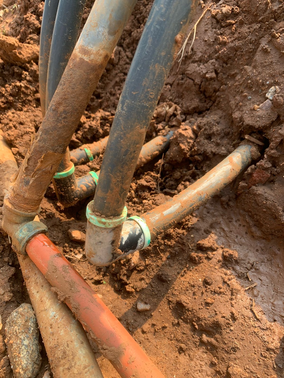 Underground leaking water pipes repaired in Pomona showing exposed PVC plumbing connections and fittings in trench during underground pipe repair and maintenance.
